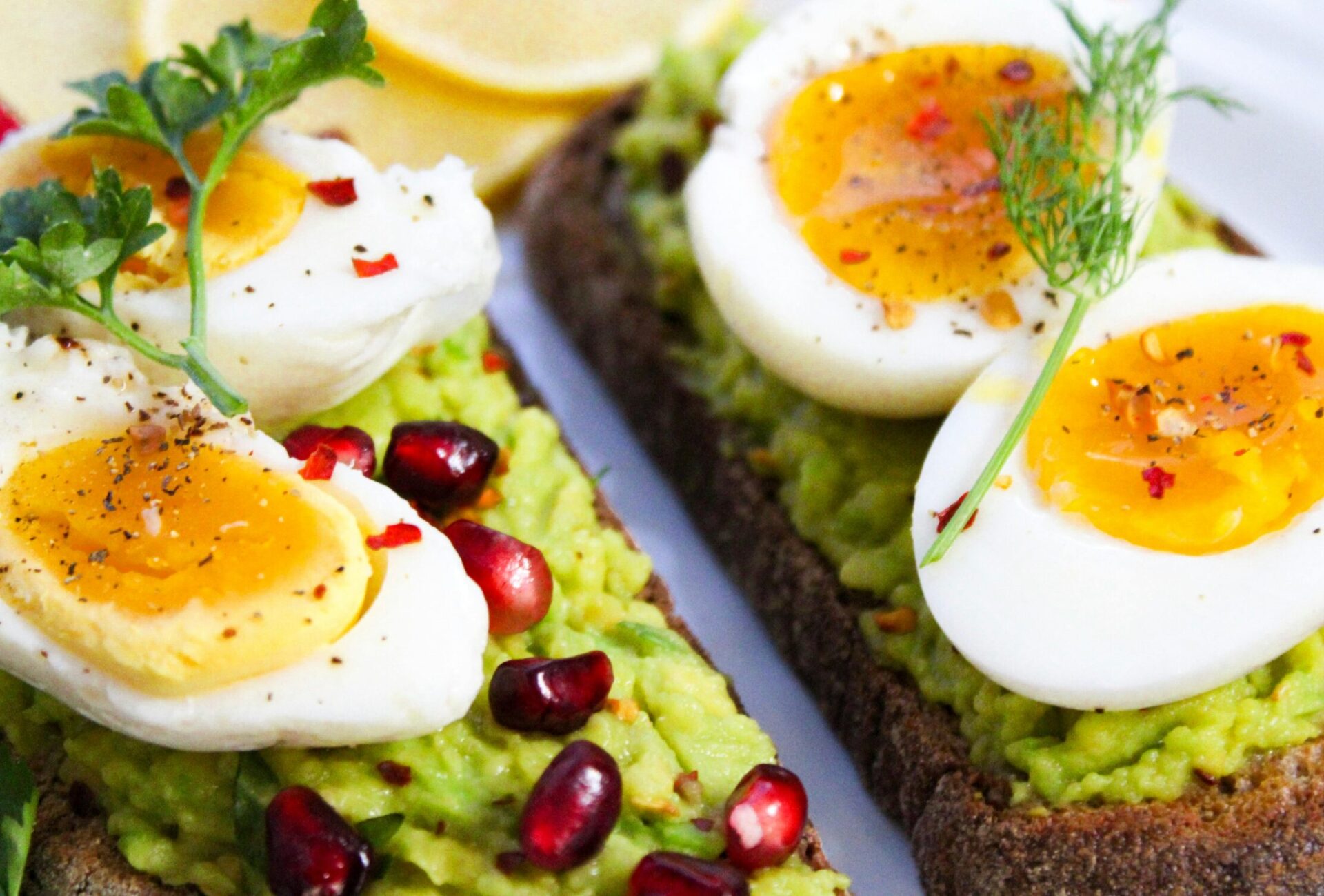 Savor this delicious avocado toast topped with soft-boiled eggs and garnished with pomegranate seeds.